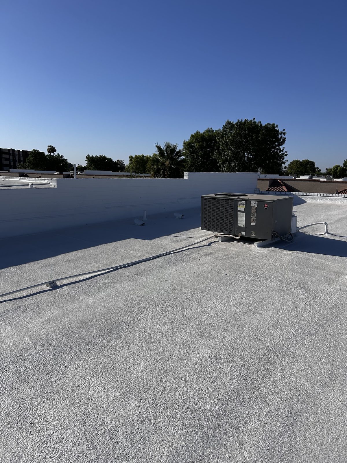 After photo of the same style of Mesa foam roof finished with a fresh white elastomeric coating and detailed rooftop equipment