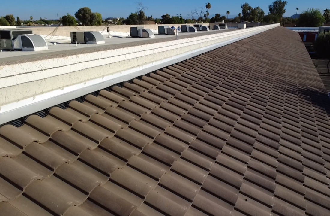 CS13 7 After photo of the same long roof run finished in new brown concrete tile beside the flat roof and parapet