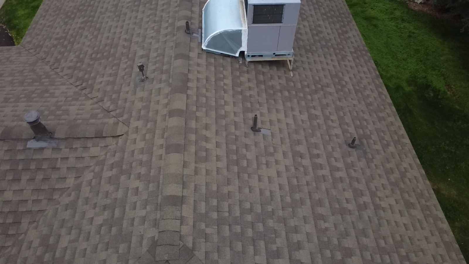 After photo of the rebuilt shop roof with new GAF Timberline Natural Shadow shingles, new galvanized pipe jacks, and the rooftop air conditioning unit reset on the finished roof