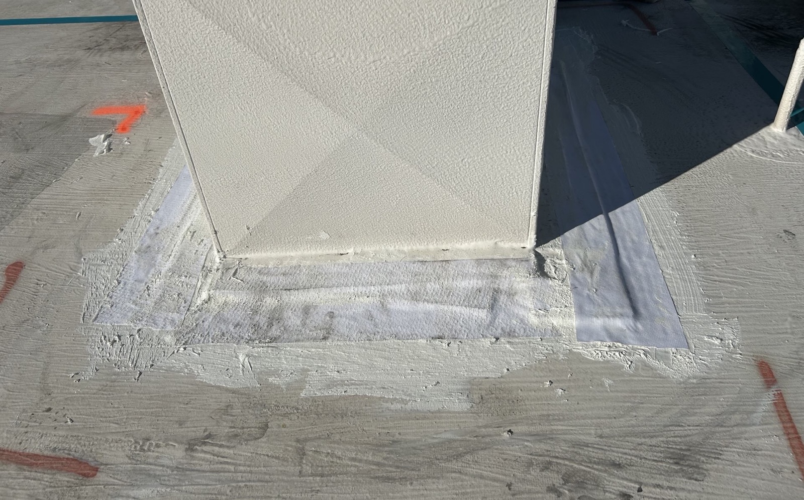 CS15 5 Progress photo of three-course silicone work at the base of a rooftop curb, with reinforcing fabric bedded into wet silicone over the TPO membrane and inspection markings still visible nearby