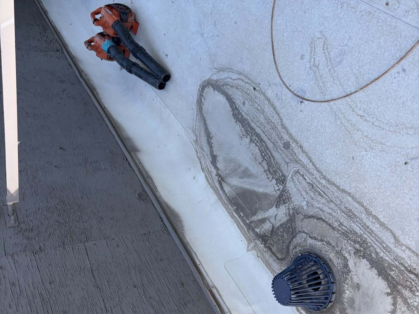 CS17 5 Work in progress photo of two leaf blowers on a Scottsdale commercial roof beside a roof drain, with grit and debris driven toward the drain strainer