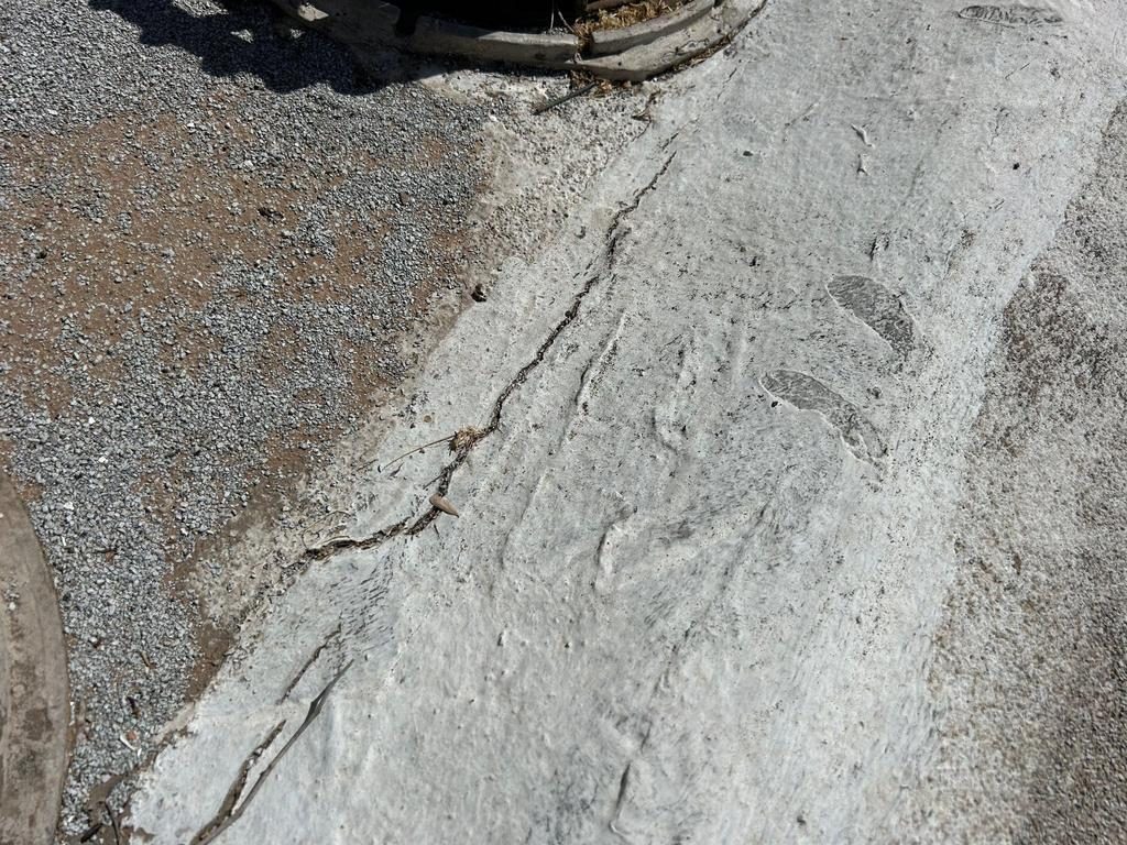 Before photo of a Phoenix commercial cap sheet roof with a long open split running through a previously patched ridge in the granulated surface