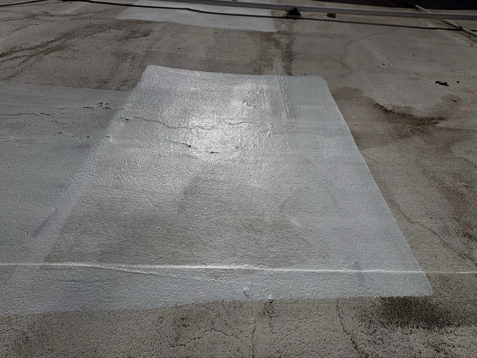 CS19 2 After photo of the same Gilbert roof area with a fresh white elastomeric coating applied over the repaired section, bordered by the older weathered coating