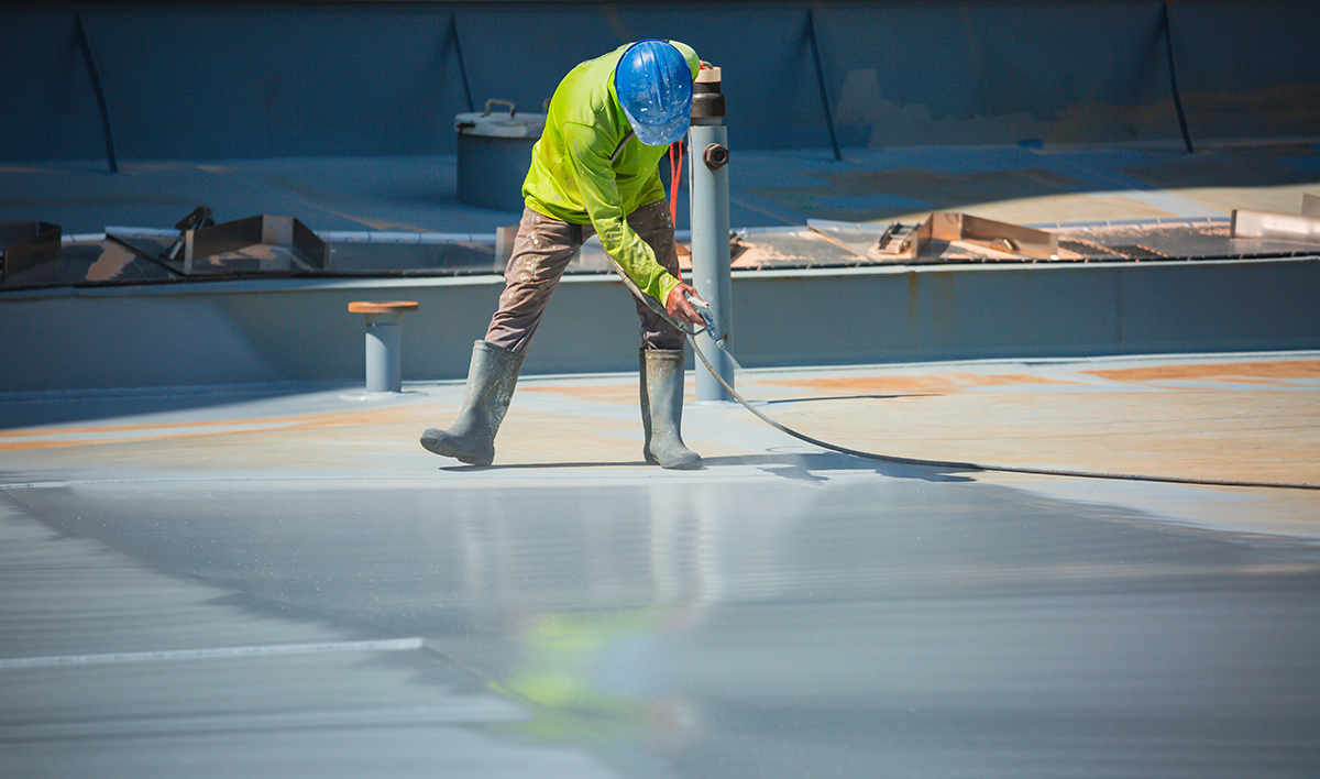A Male Worker Holding An Industrial Spray Gun Used For Roof Plat