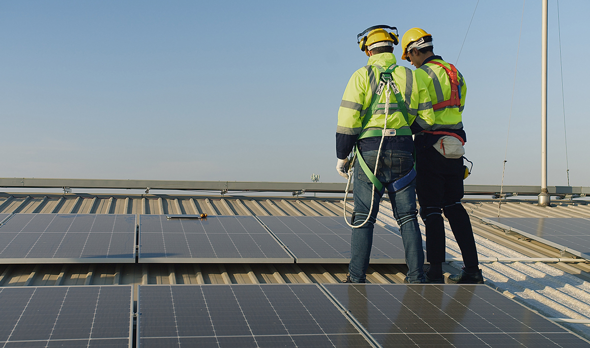 Technicians Engineer In Safety Vests And Helmets Discussing Analysis Maintenance Install Solar Panels On A Metal Roof, Integrating Sustainable Energy Solutions