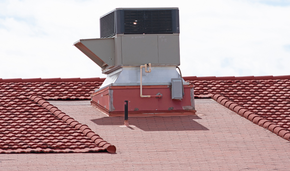 Large Air Conditioning Unit On A Sloped Red Clay Tile Roof Of A