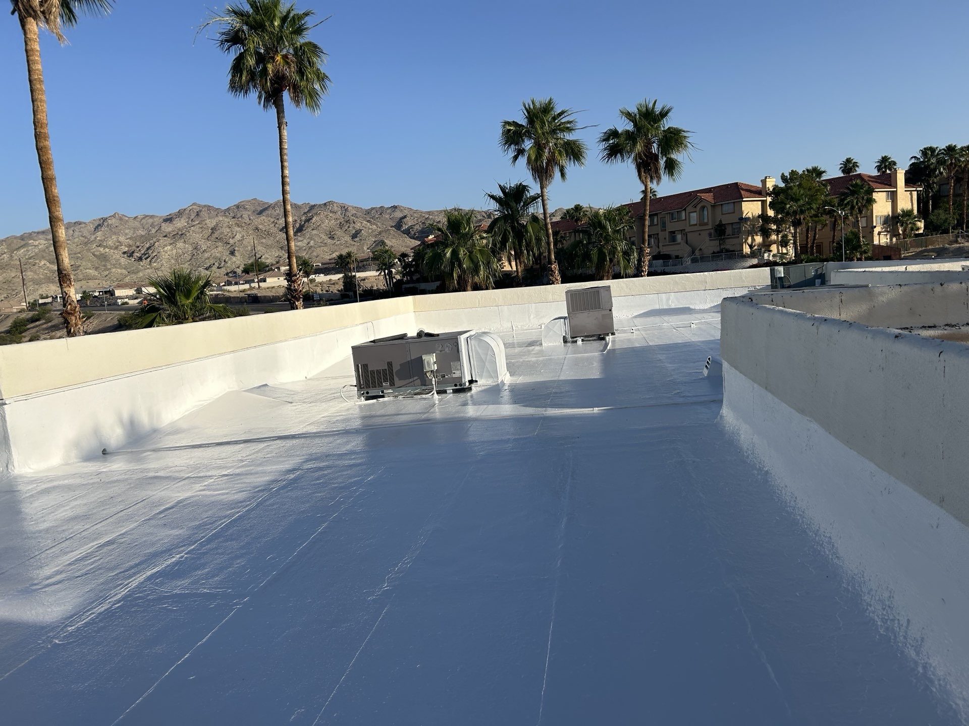 After photo showing the freshly applied white silicone coating on the Laughlin commercial roof