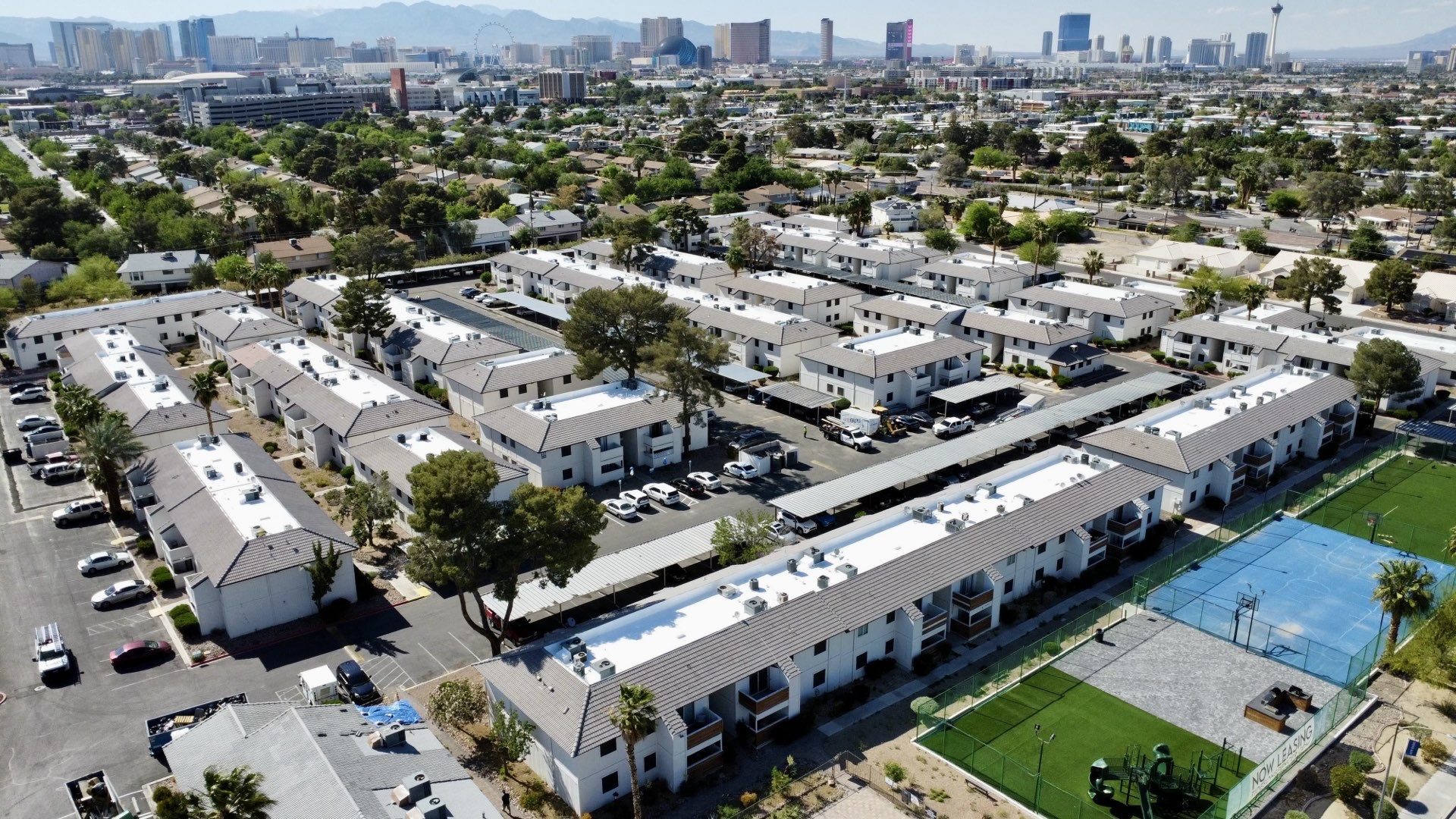 Aerial after photo of the recoated roofs across the Las Vegas apartment community with the Strip skyline in the background