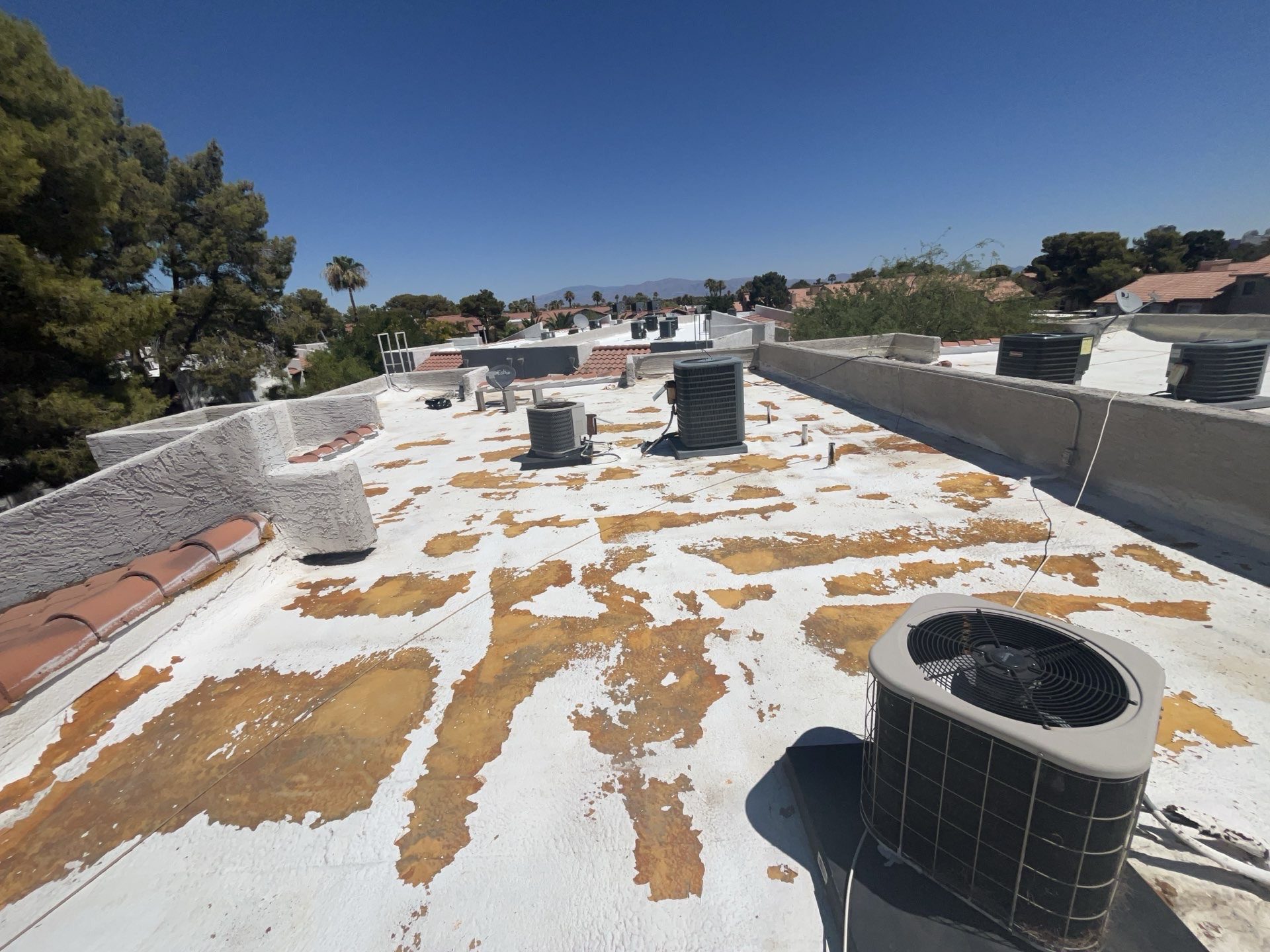 Before photo of an aging foam roof in a Las Vegas apartment community with peeling coating and exposed patches