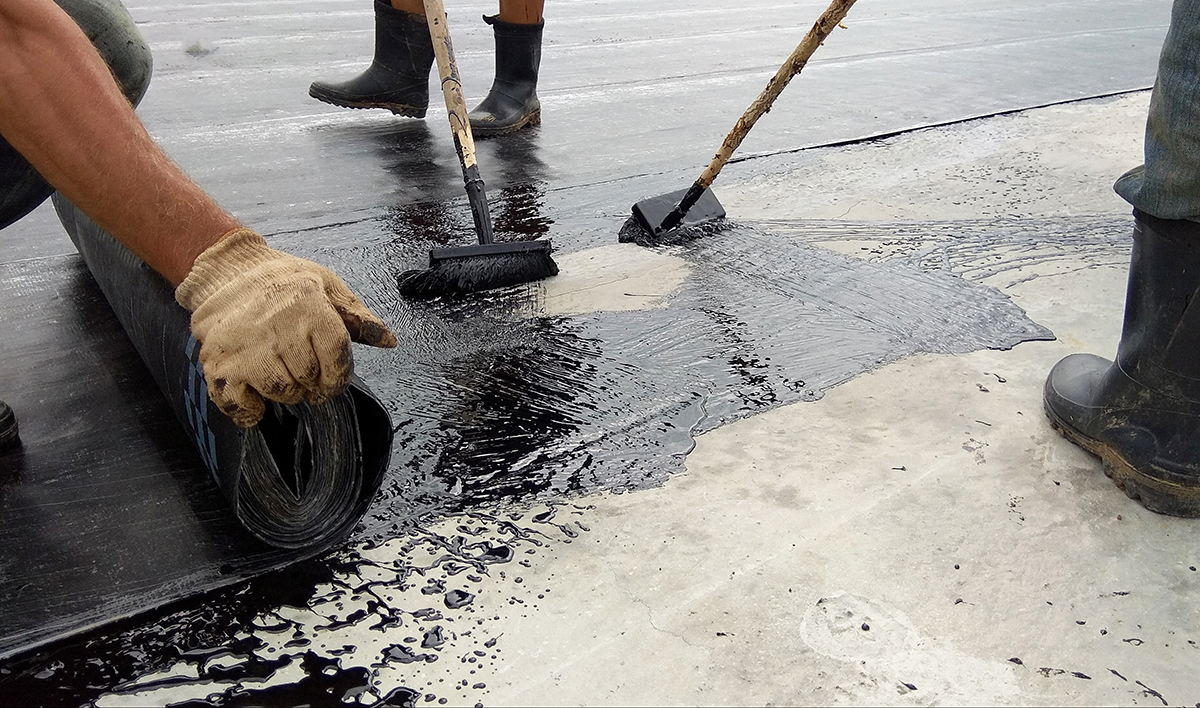 Roofer Worker Painting Bitumen Praimer At Concrete Surface By The Roller Brush Waterproofing