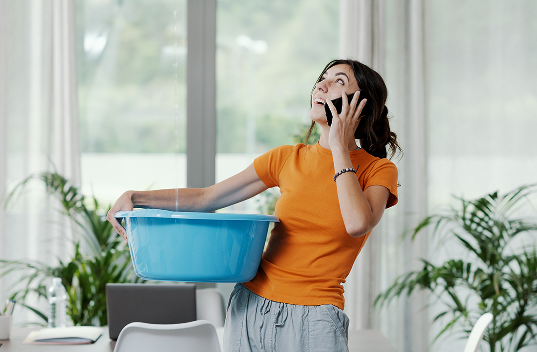 Woman Collecting Water Leaking From The Ceiling
