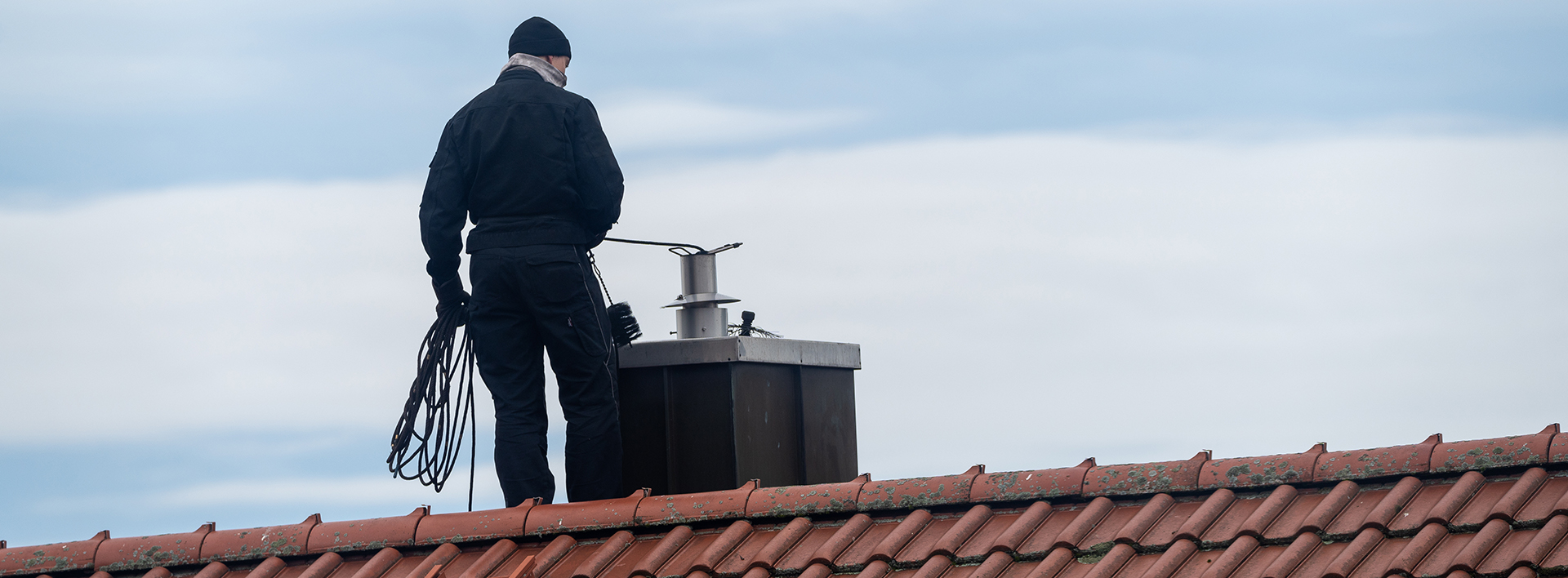 Chimney Sweeper On The Roof Of A House In An Attempt Of Chimney Sweeping